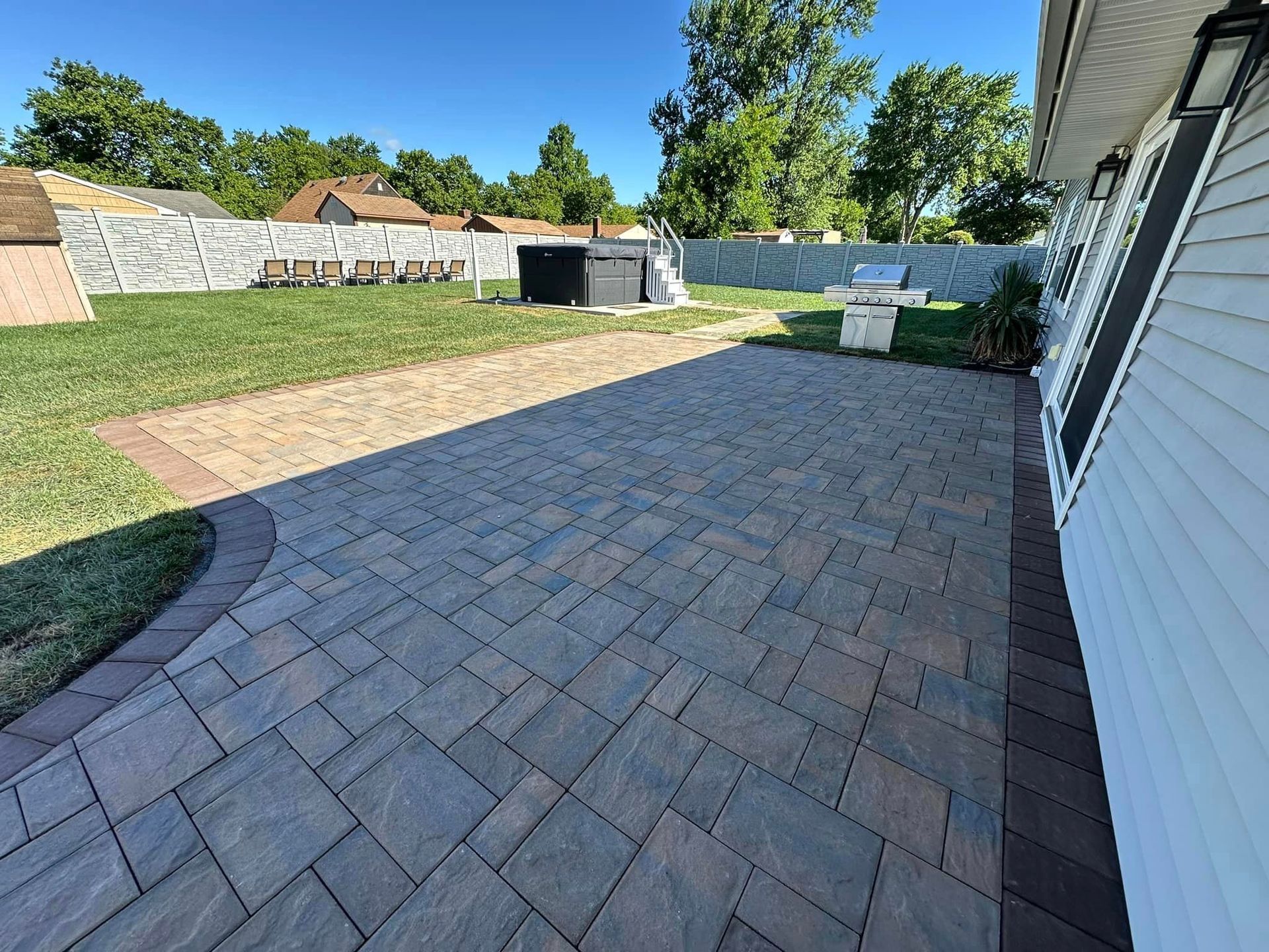 A patio with a grill in the backyard of a house.