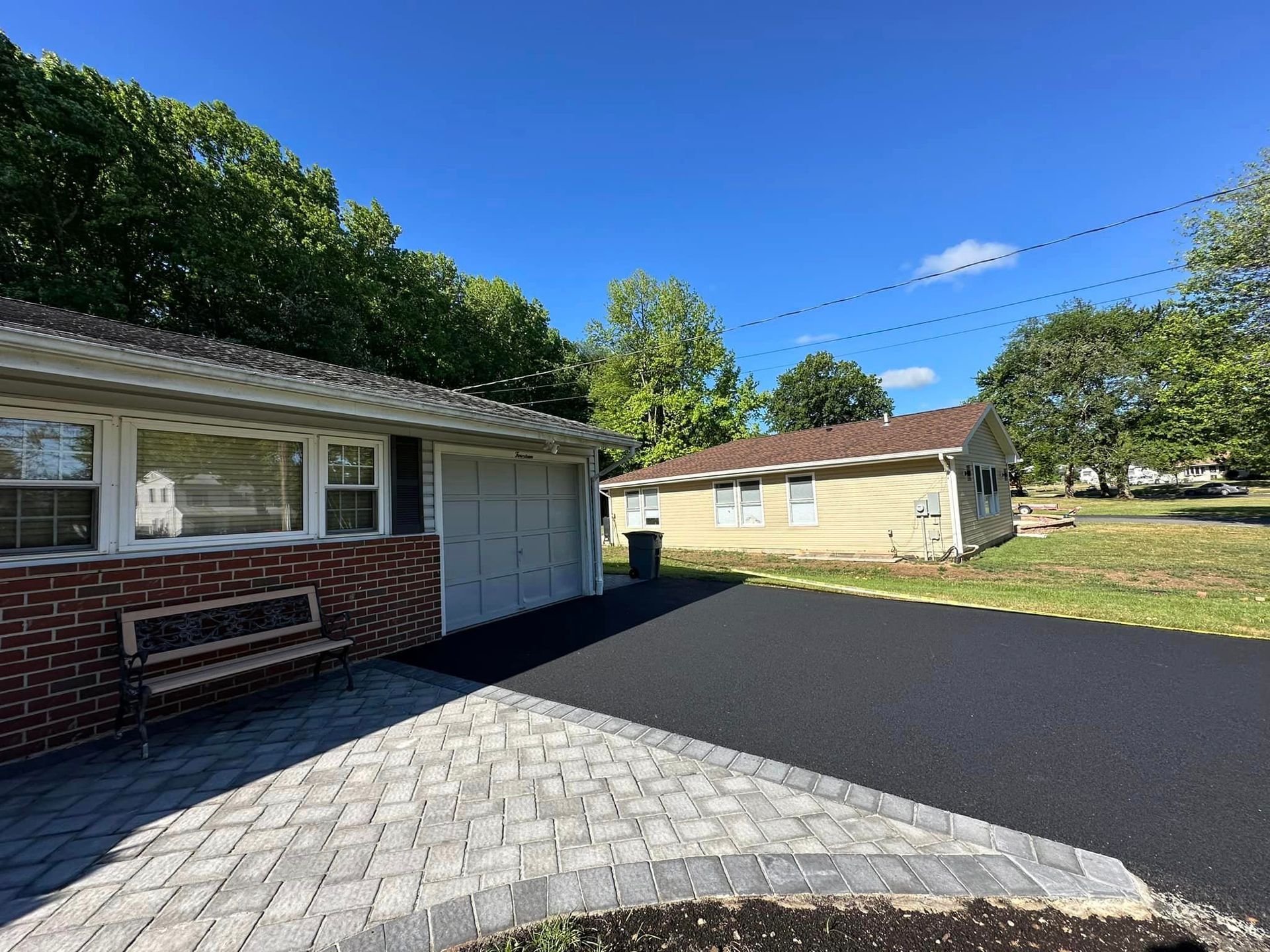 A house with a garage and a bench in front of it.
