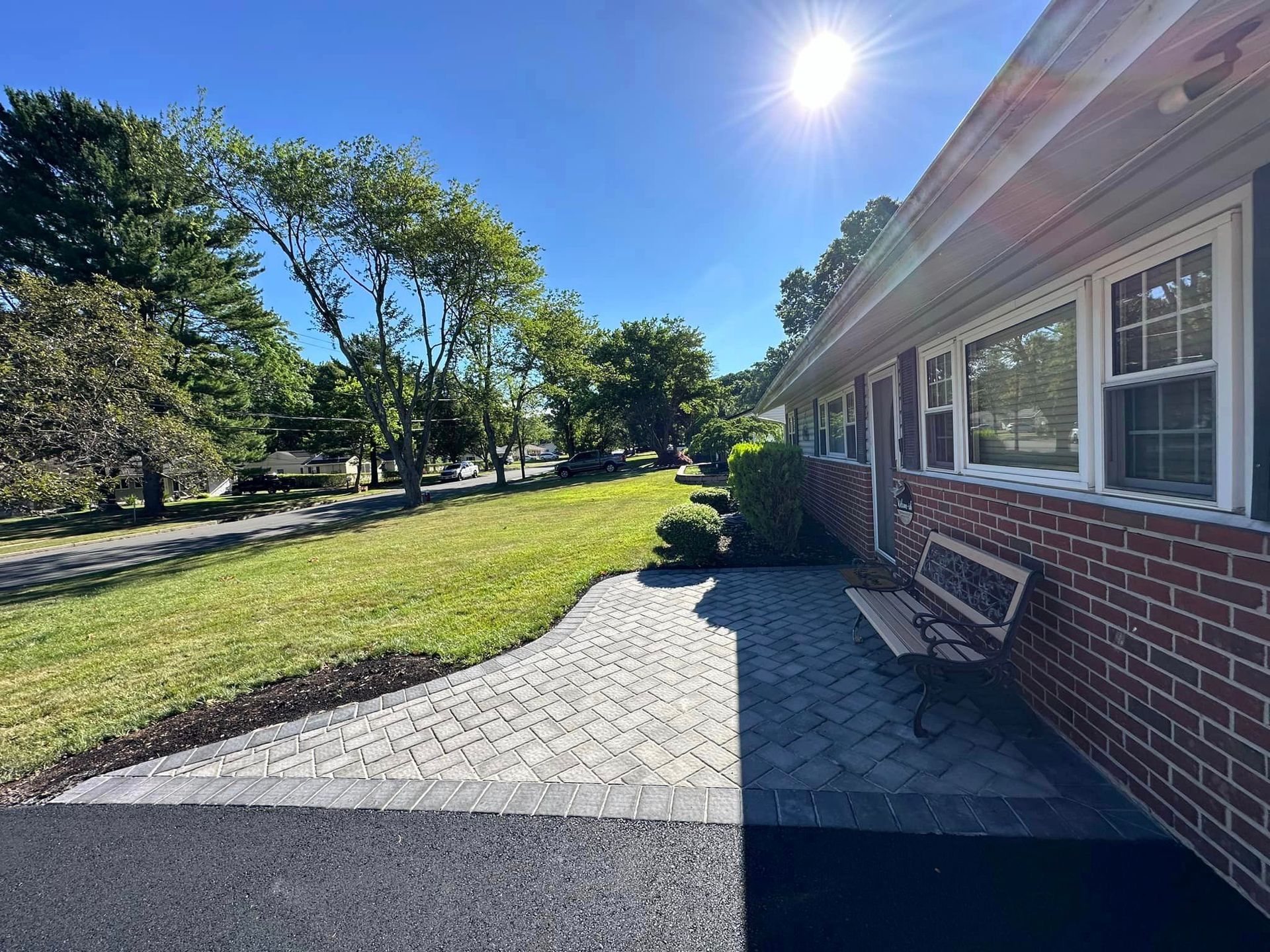 A brick house with a bench in front of it on a sunny day.