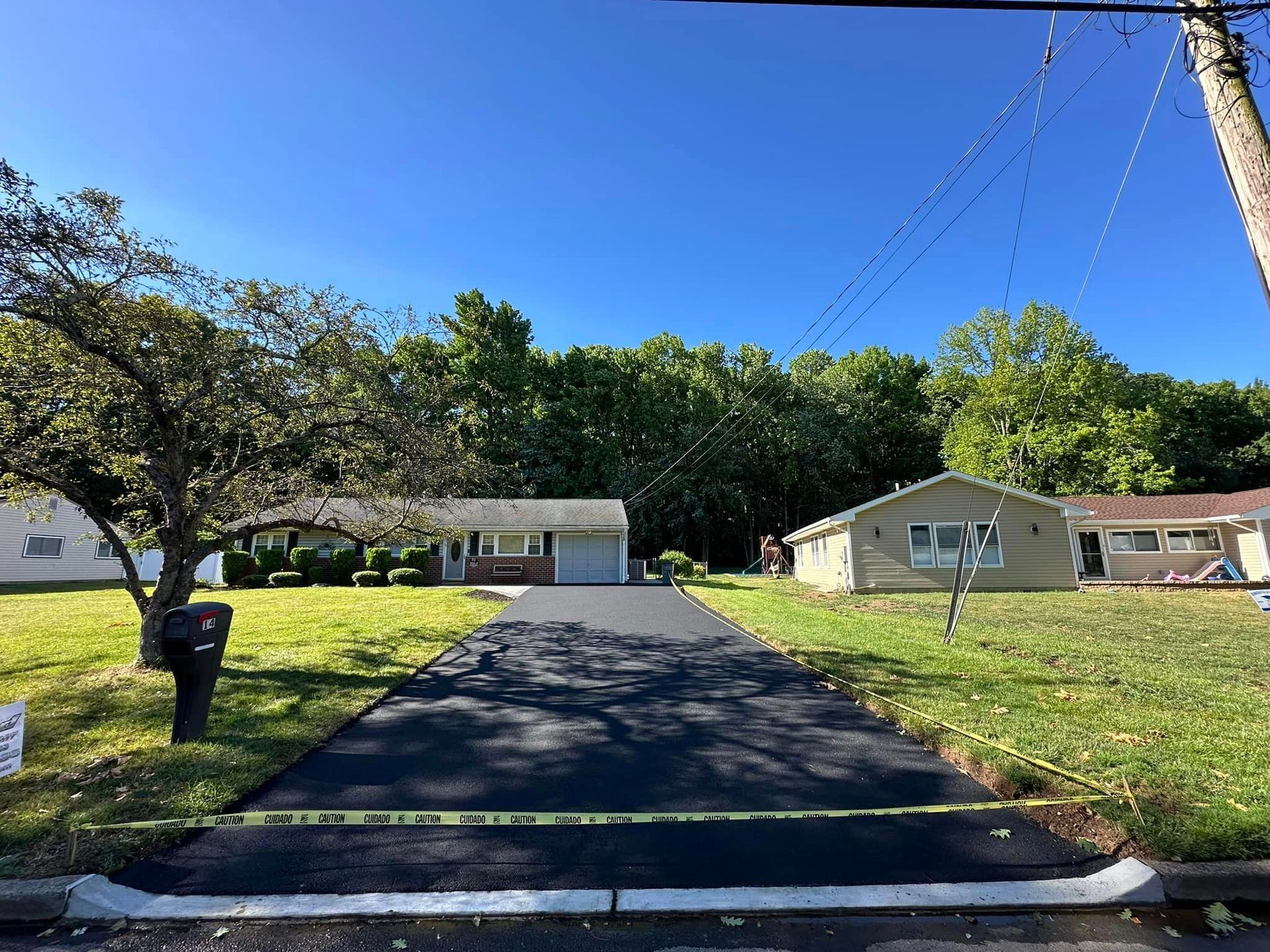 A driveway leading to a house with a lot of grass and trees.