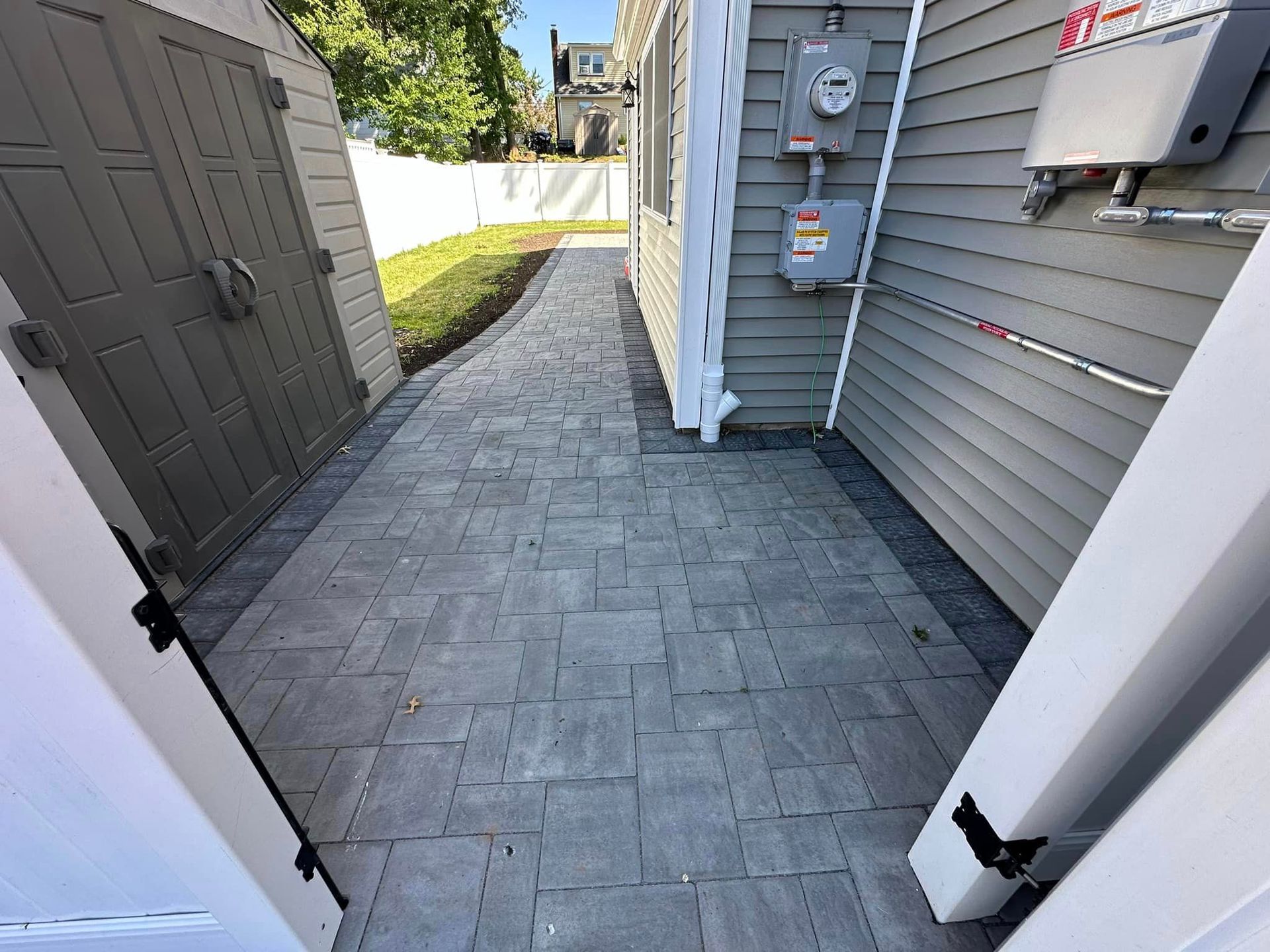 A brick walkway leading to a garage and a house