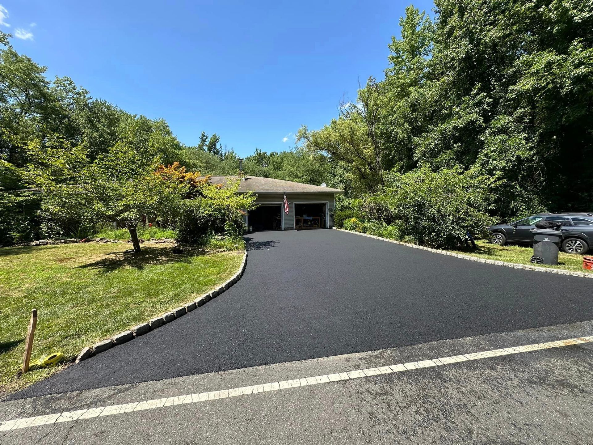 A driveway leading to a house surrounded by trees and grass.