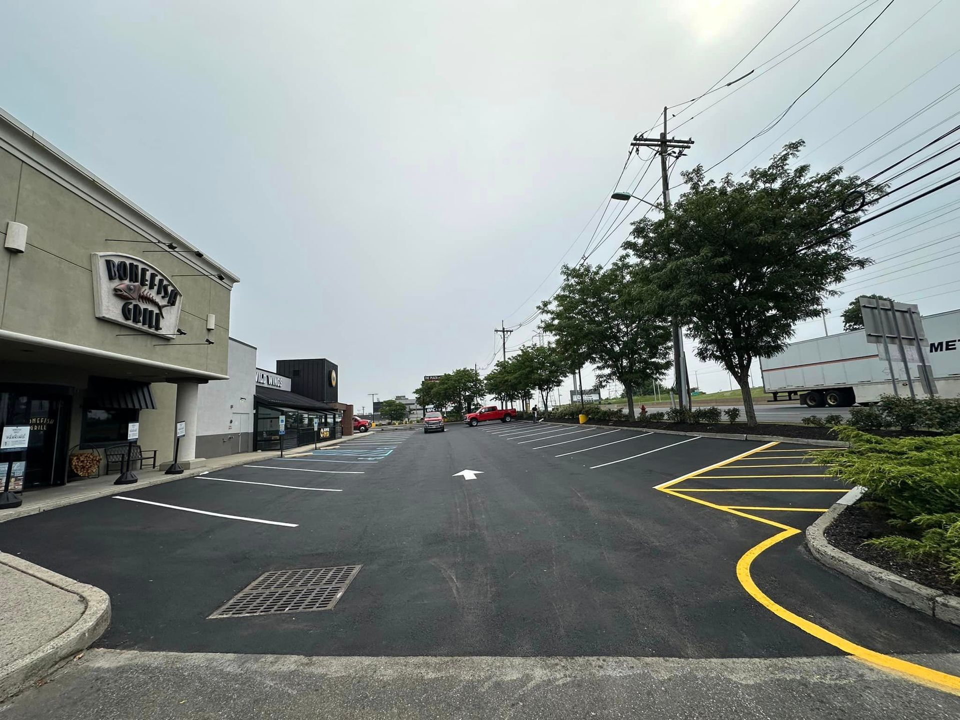 A car is driving down a street next to a parking lot.