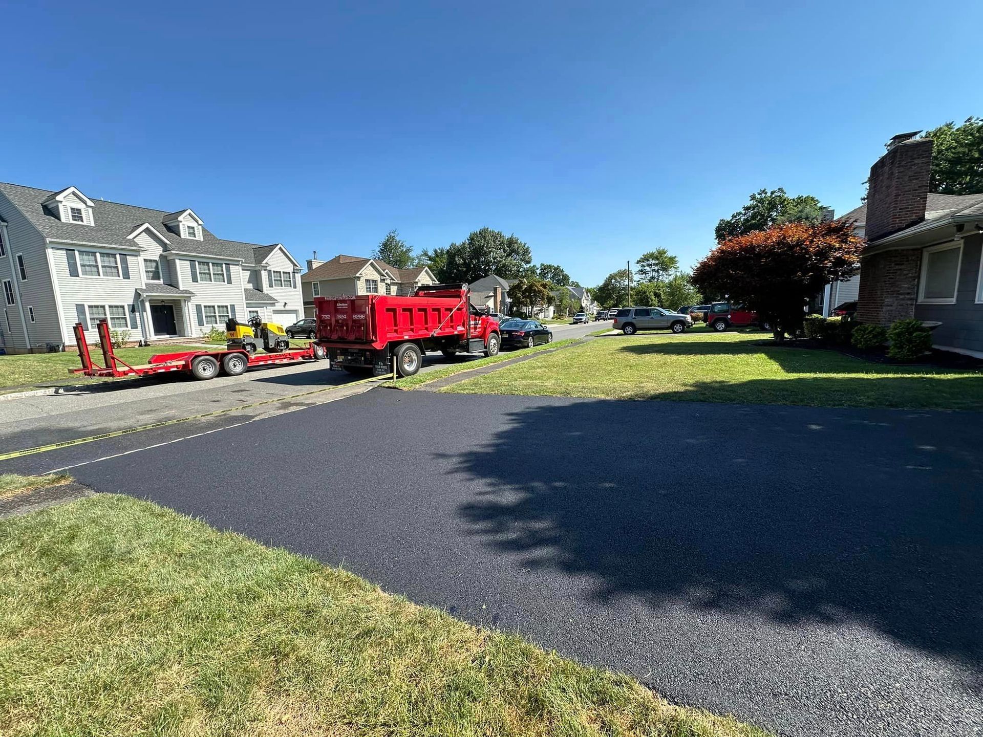 A red dump truck is parked on the side of the road in a residential neighborhood.