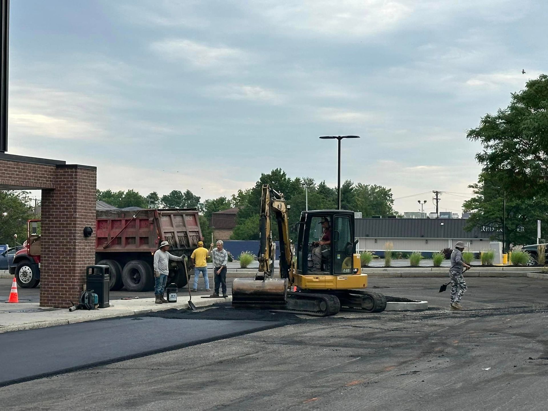 A group of construction workers are working on a parking lot.