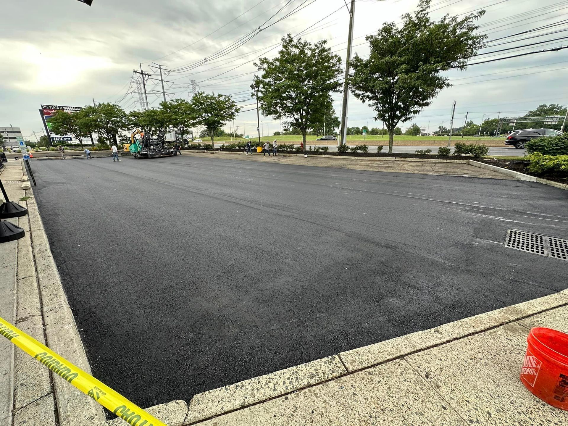 A parking lot is being paved with black asphalt.