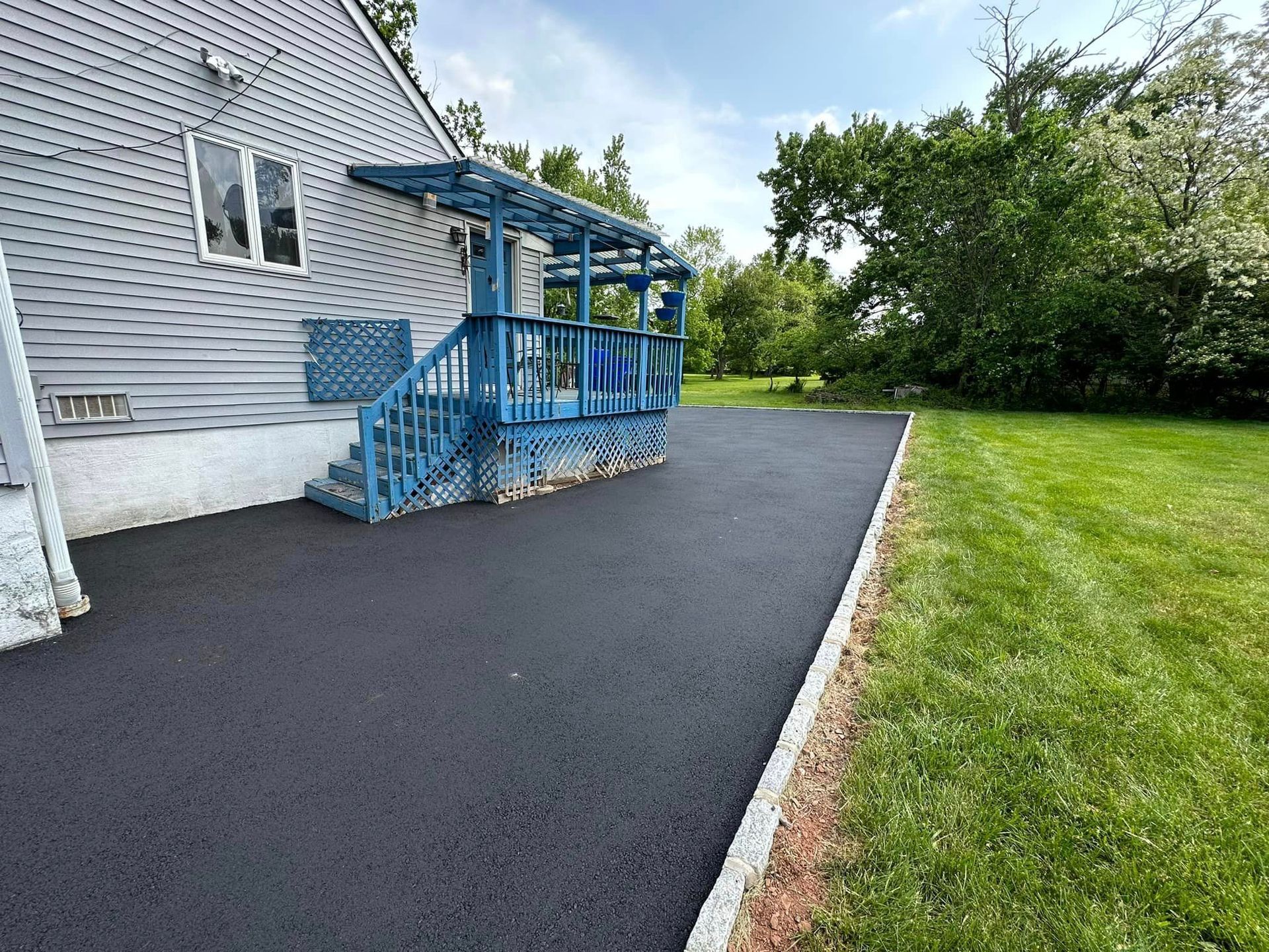 A driveway leading to a house with a blue porch and stairs.