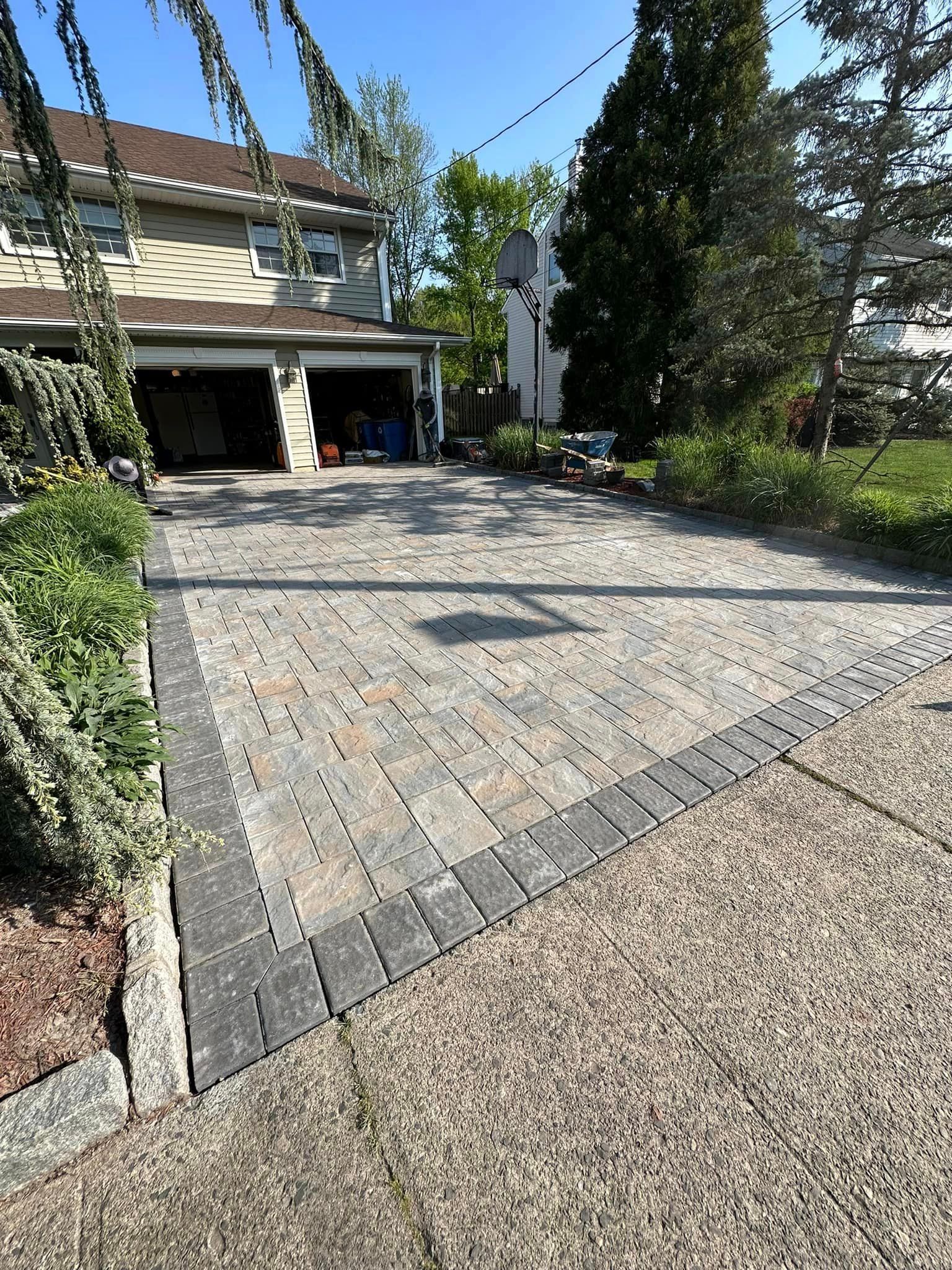 A driveway leading to a house with a garage and a basketball hoop.