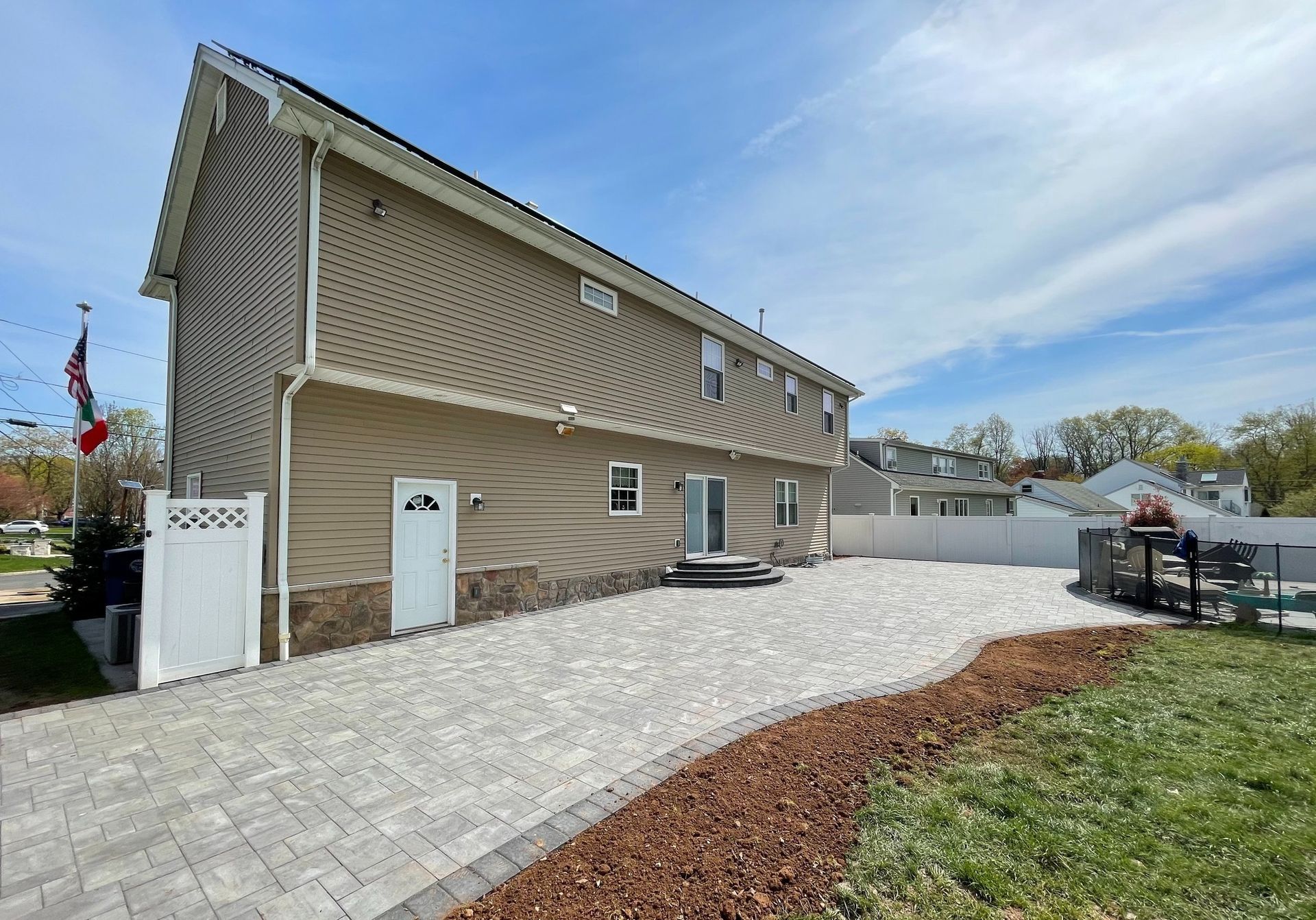 A house with a brick driveway and a fence in front of it