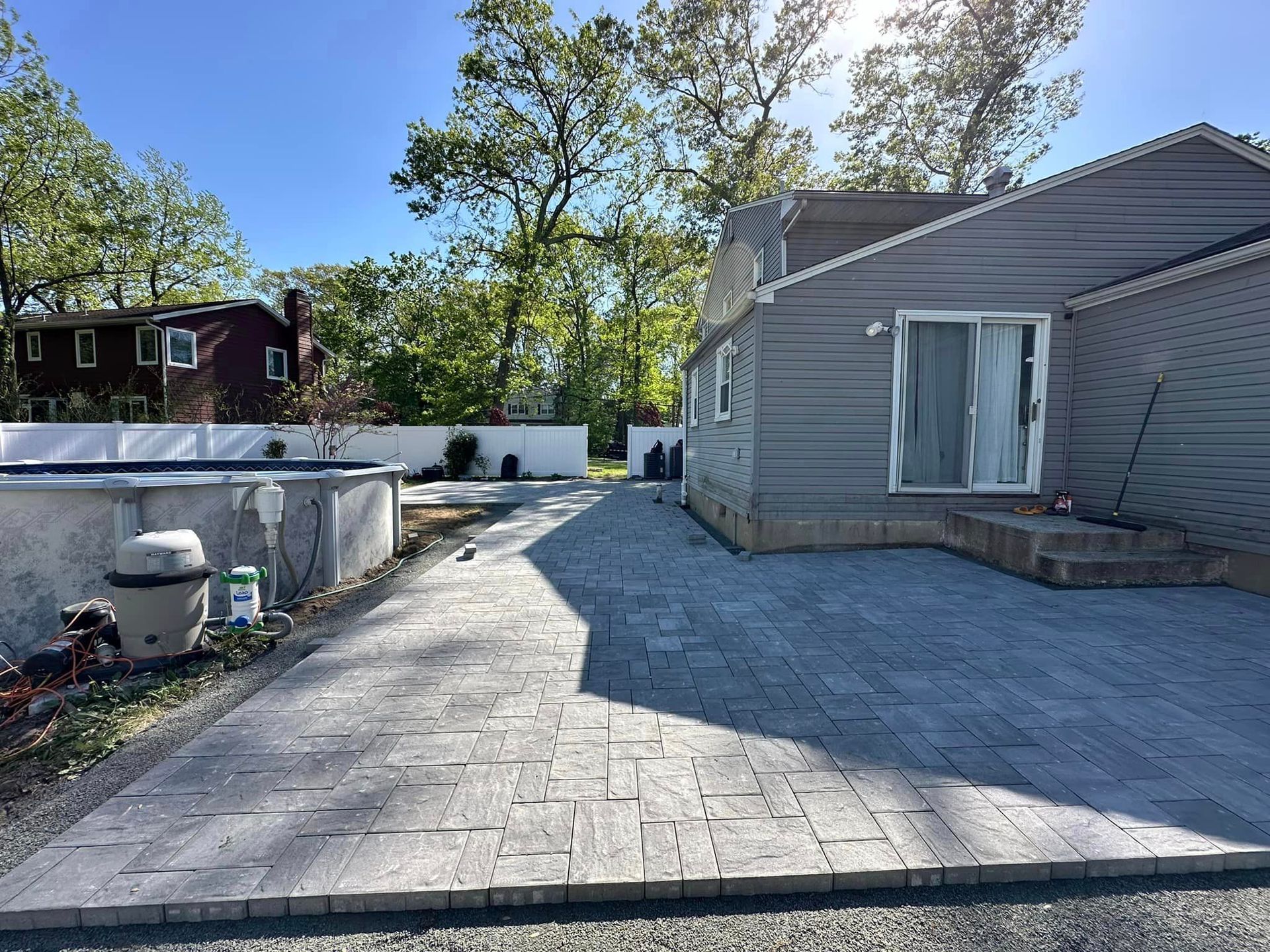 A driveway leading to a house with a pool in the background.