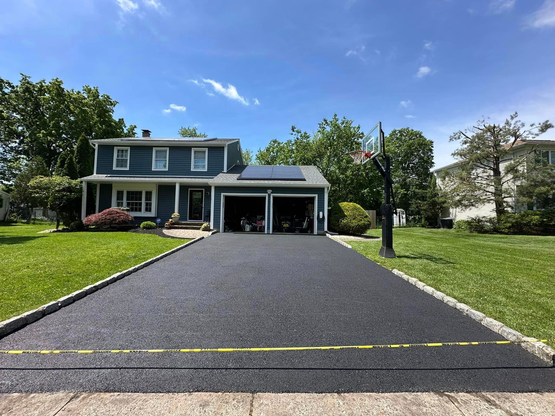A house with a driveway and a basketball hoop in front of it.