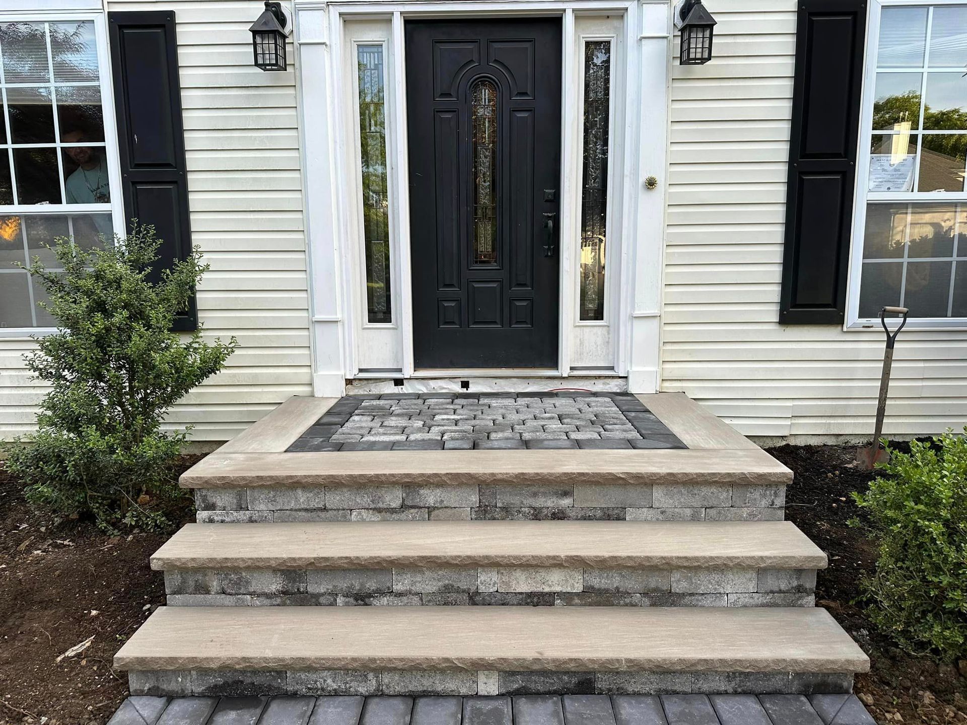 A house with a black door and steps in front of it.