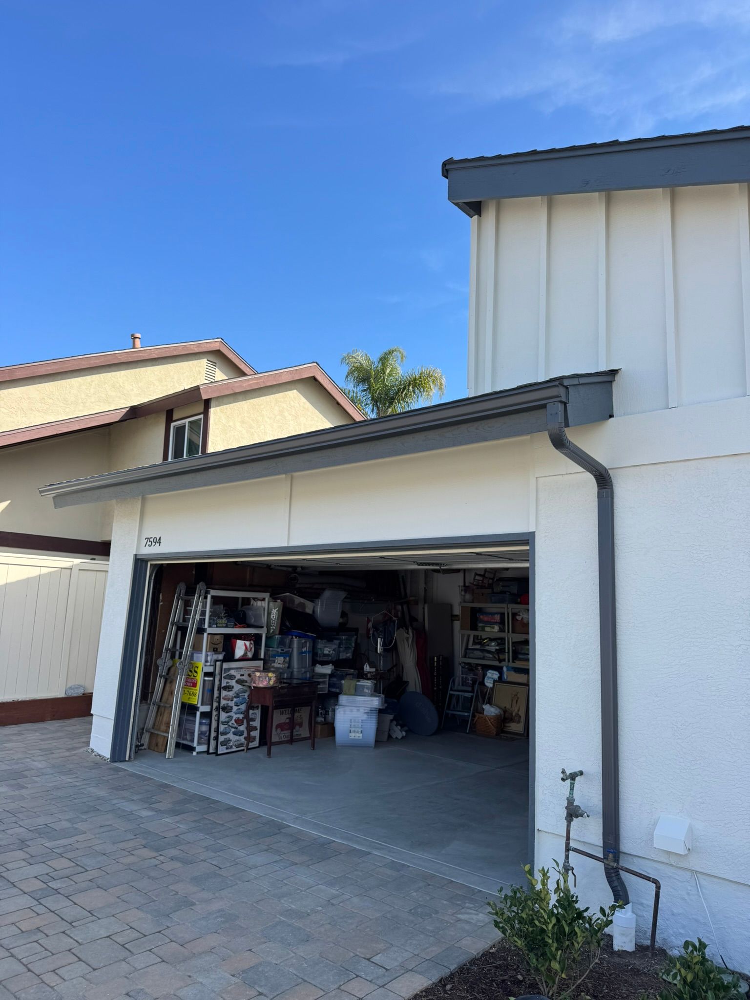 A white house with a garage with a lot of stuff in it