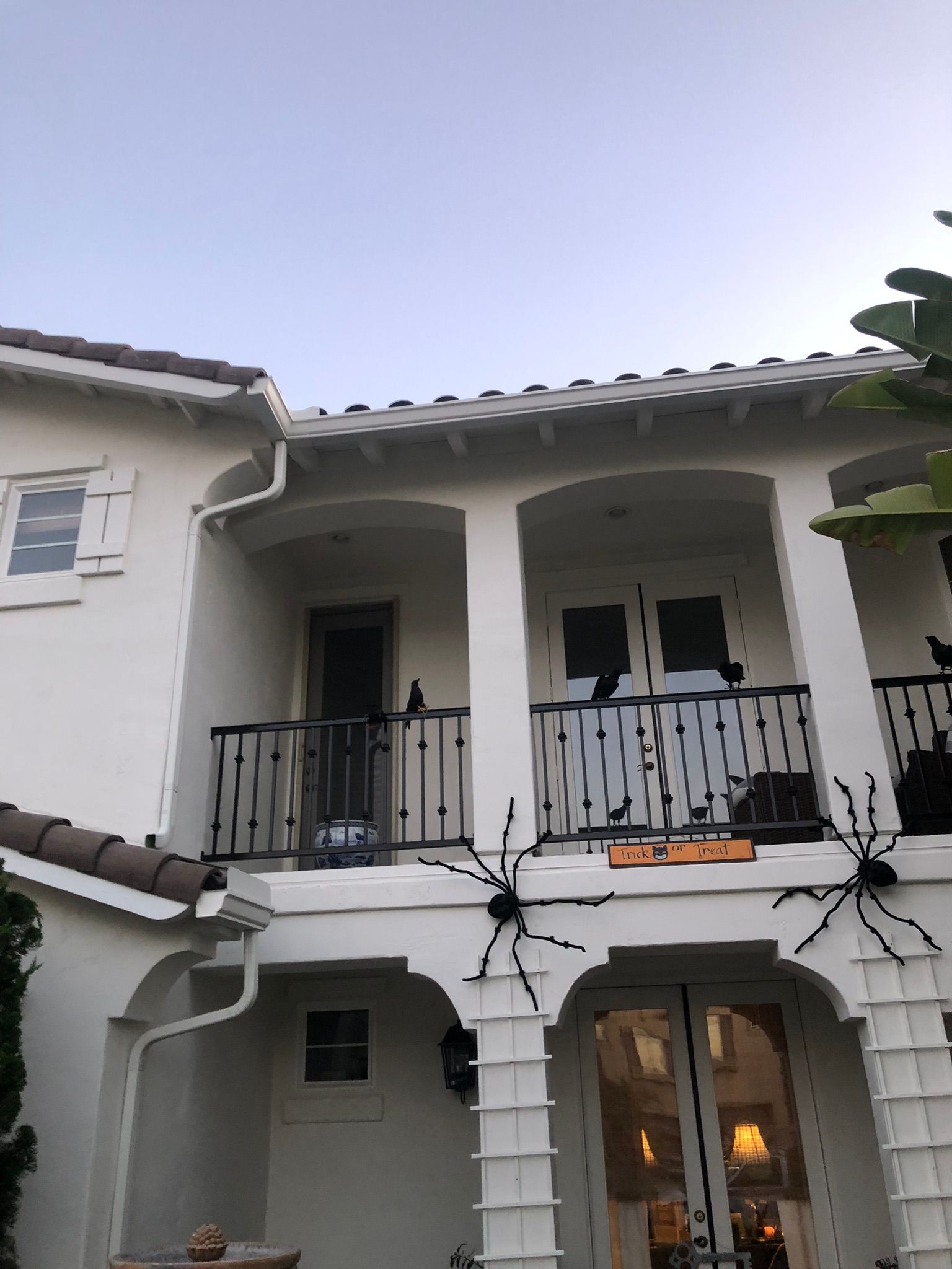 A white house decorated for halloween with spiders on the porch