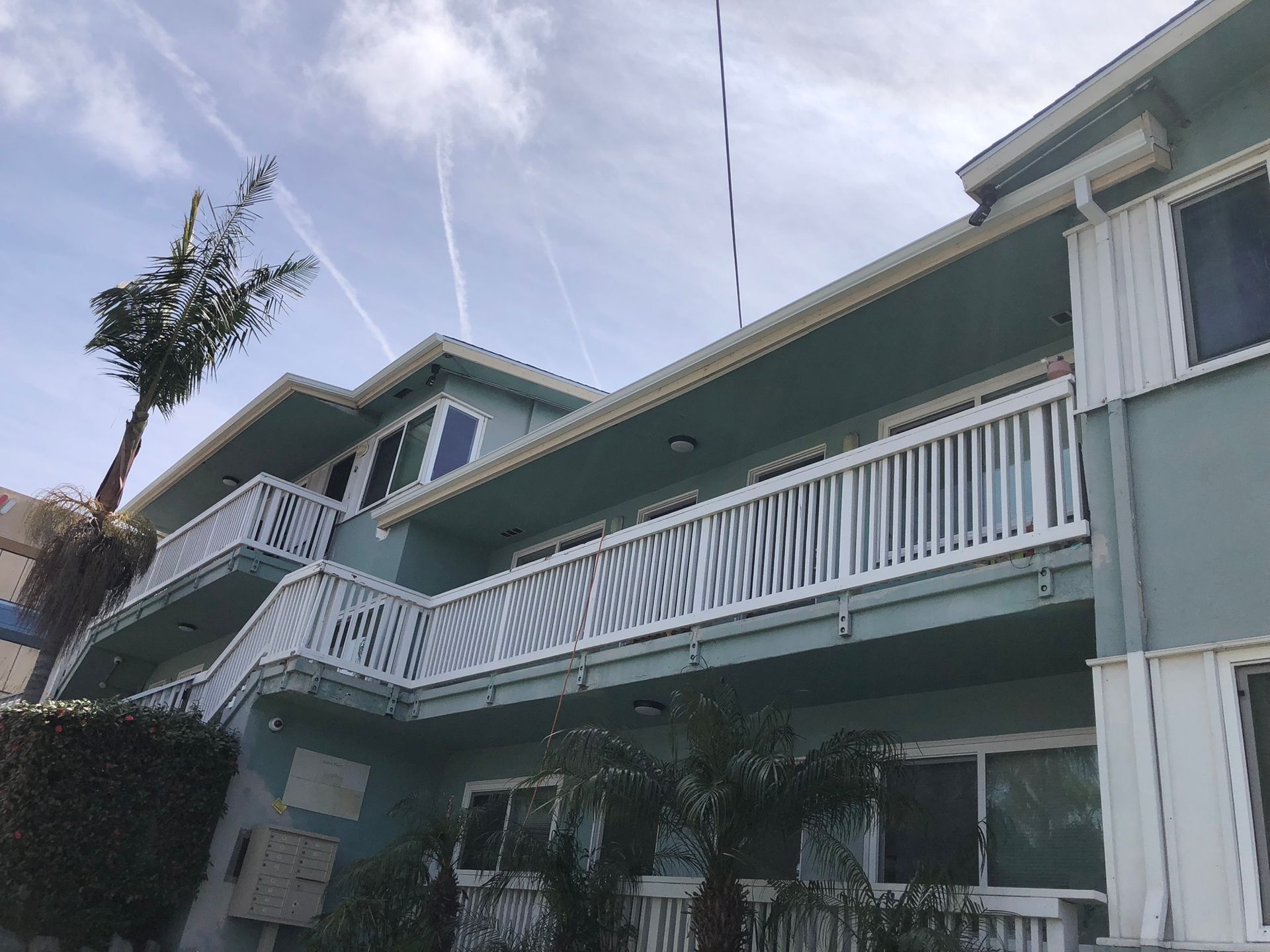 A building with a balcony and a palm tree in front of it