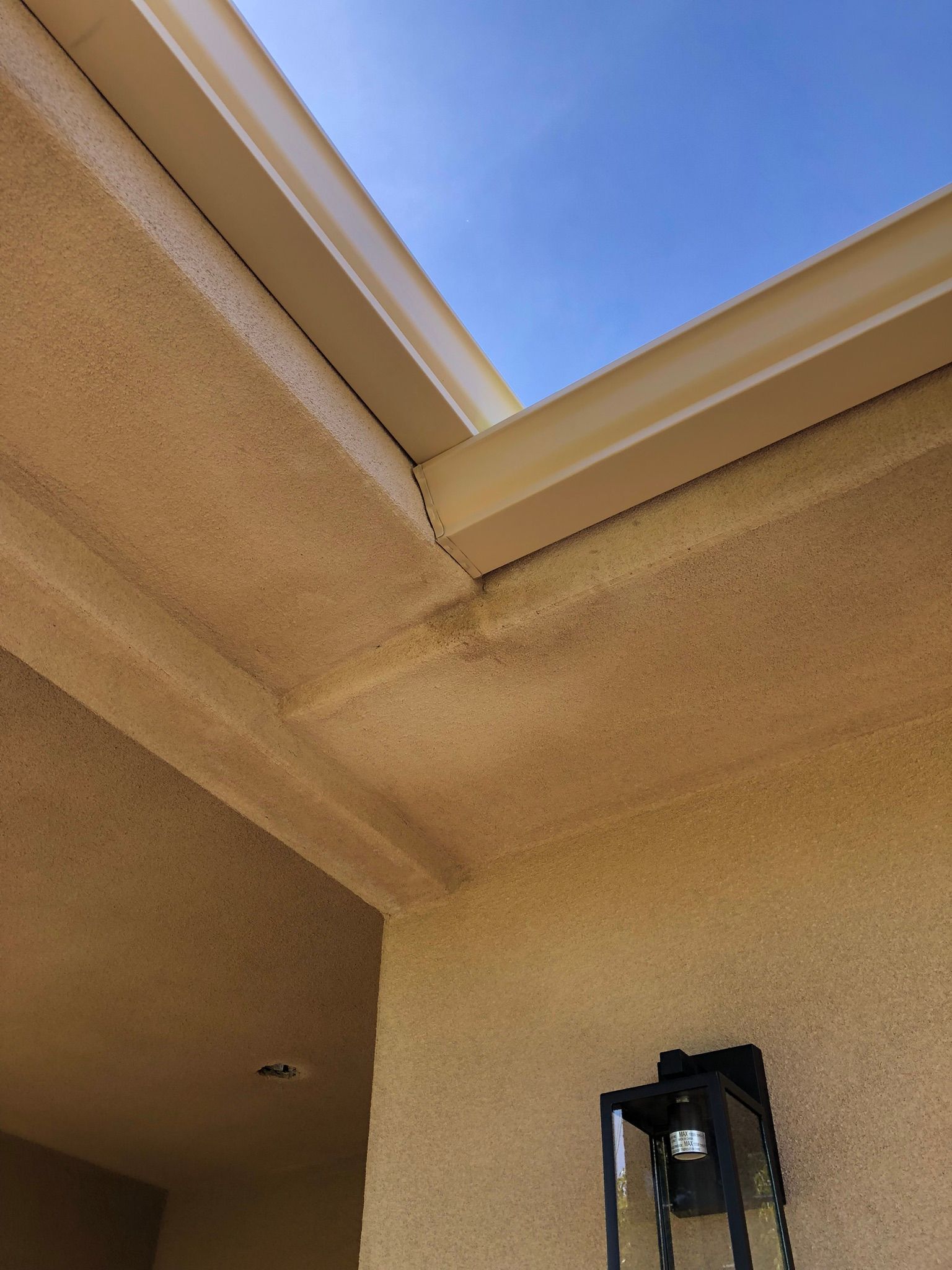A gutter on the side of a building with a blue sky in the background.
