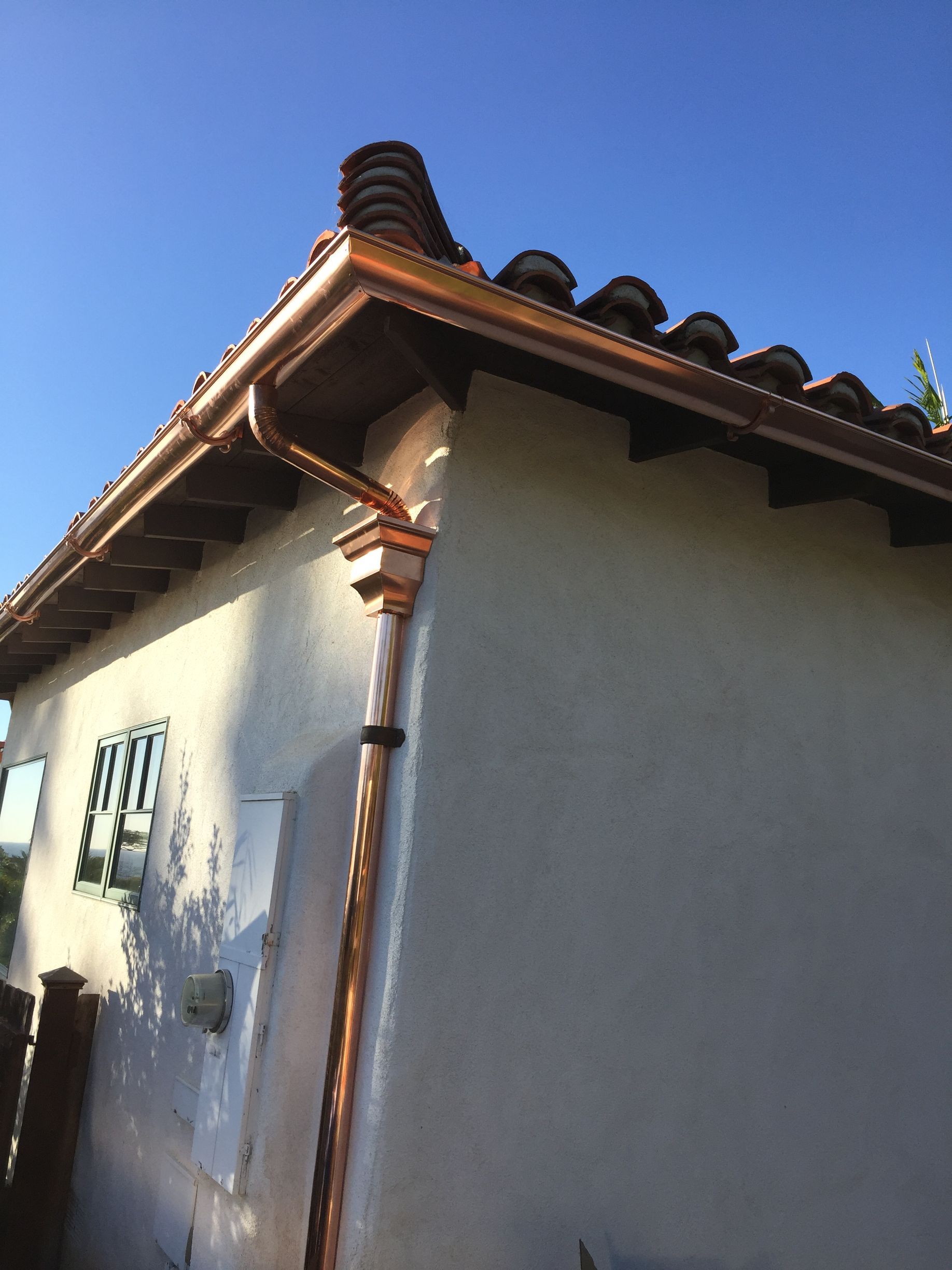 A white building with a copper gutter on the side