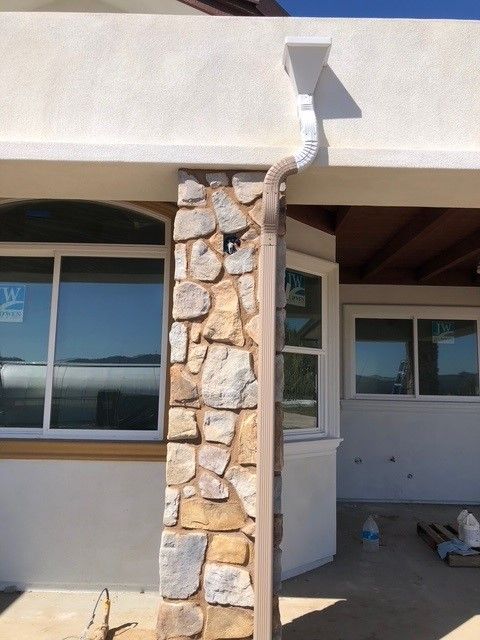 A house with a stone wall and a white gutter