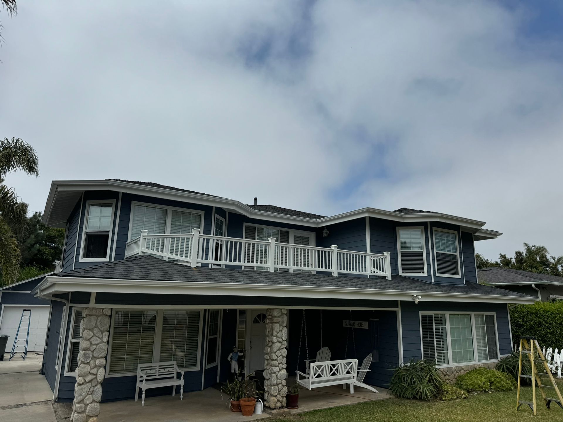 A large blue house with a white porch and a swing.