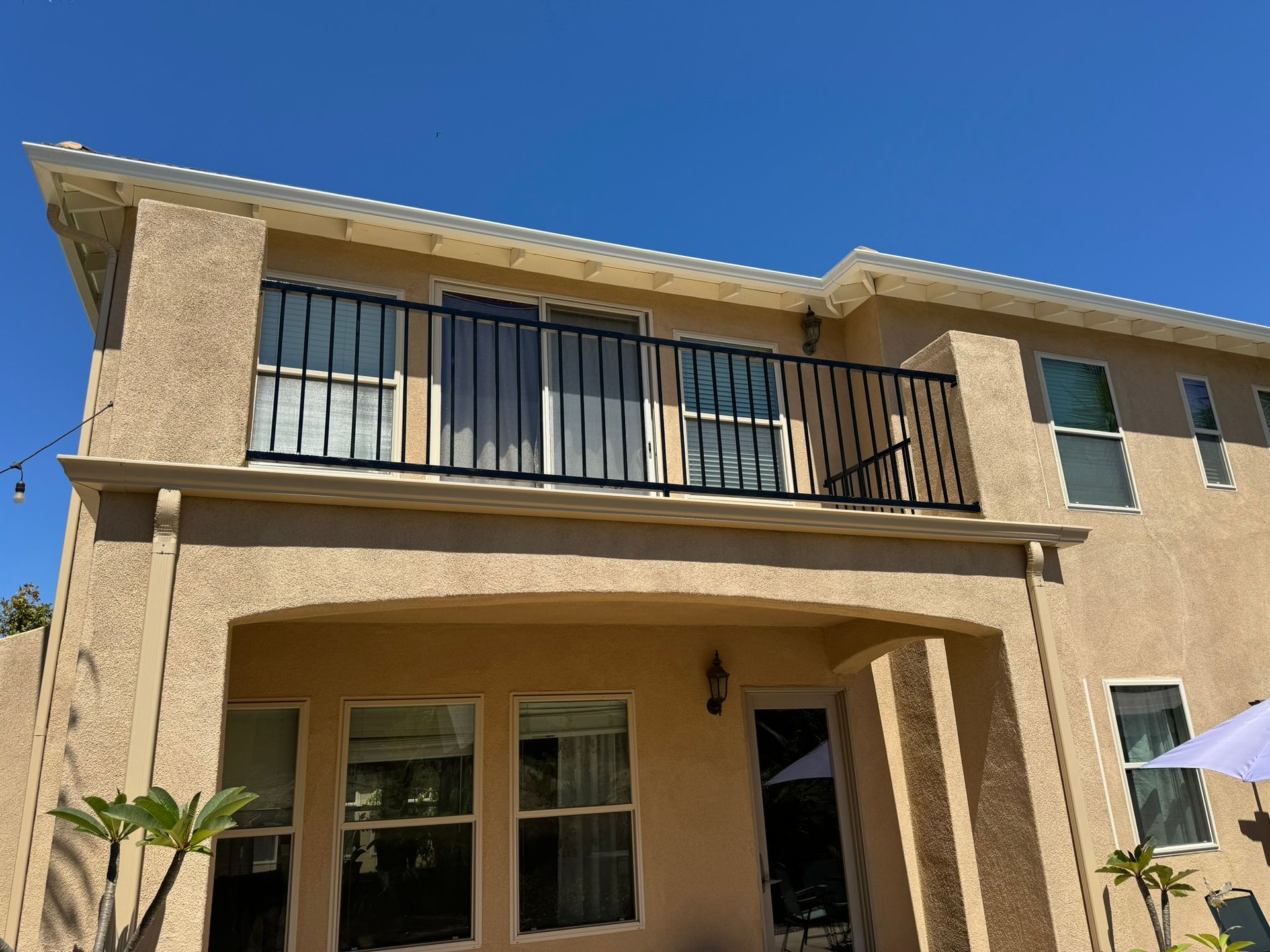 A house with a balcony and a blue sky in the background