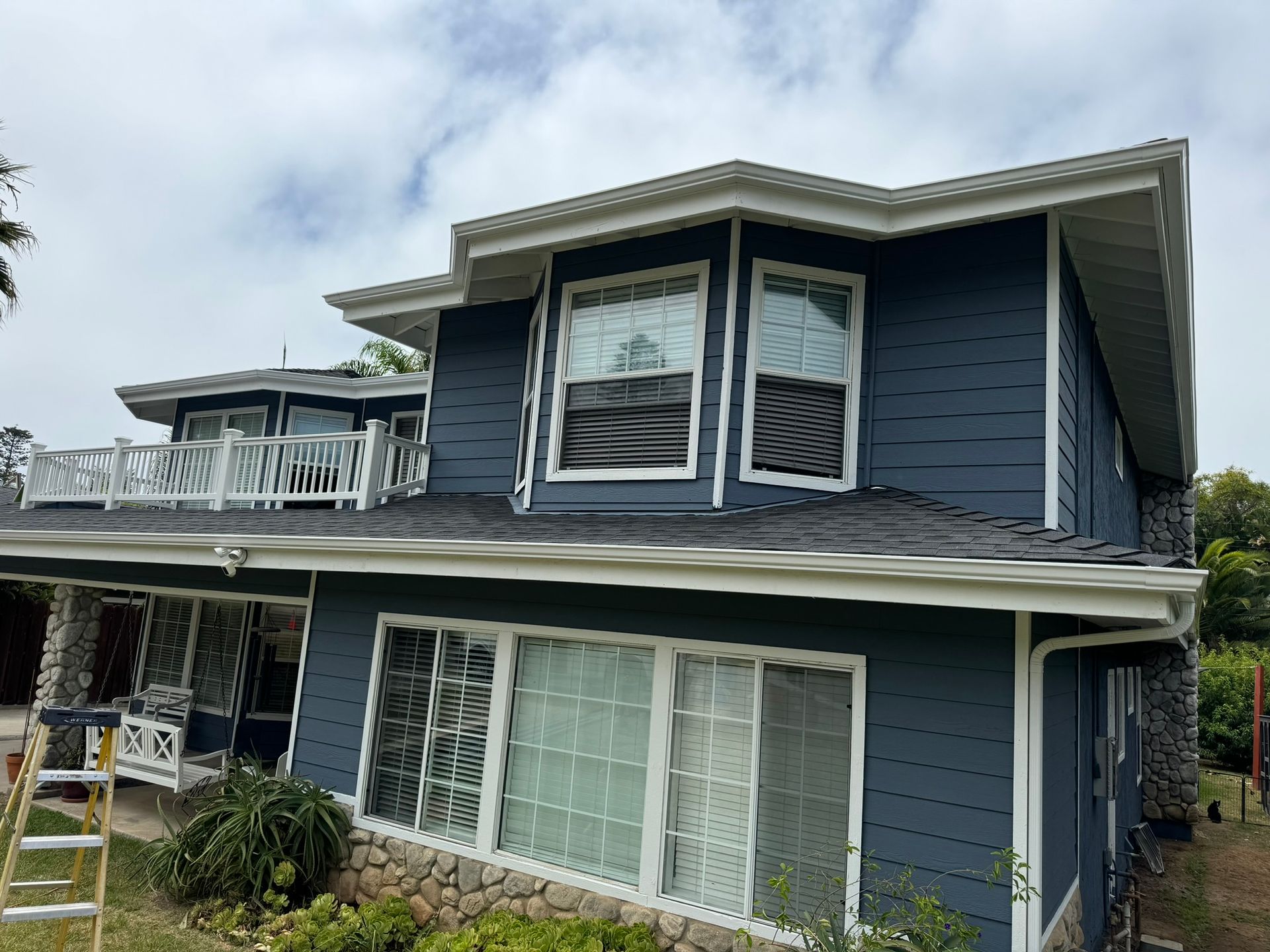 A large blue house with white trim and a balcony.
