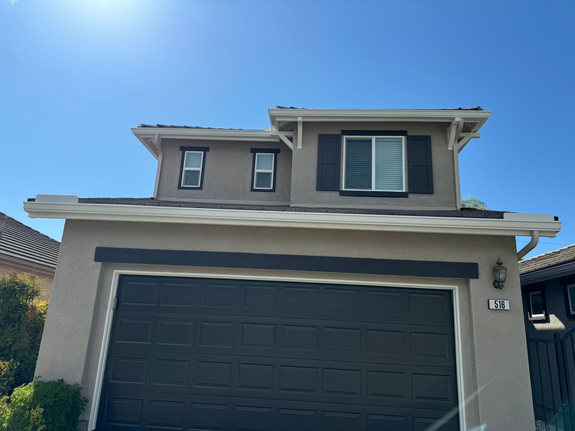 A house with a black garage door and a blue sky in the background.