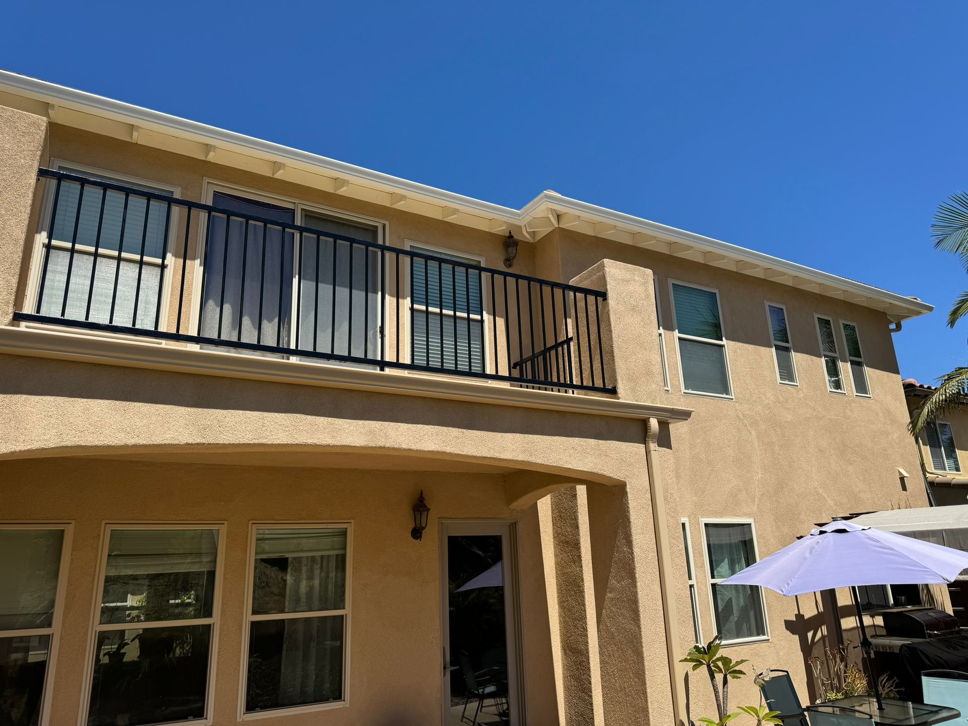 A large house with a balcony and a purple umbrella