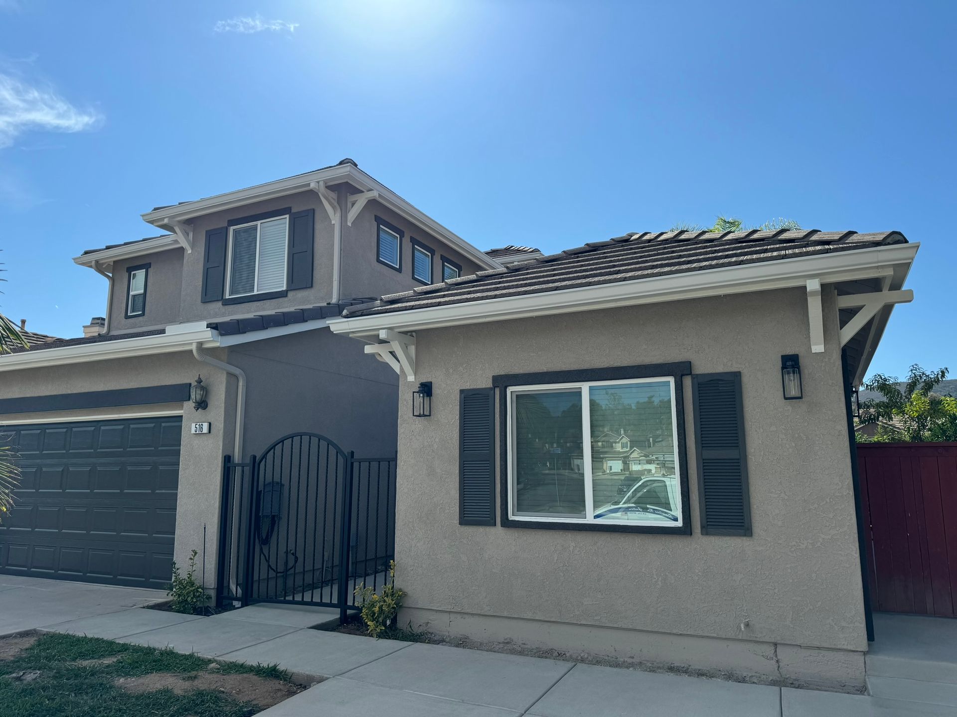 A house with a garage and a fence in front of it on a sunny day.