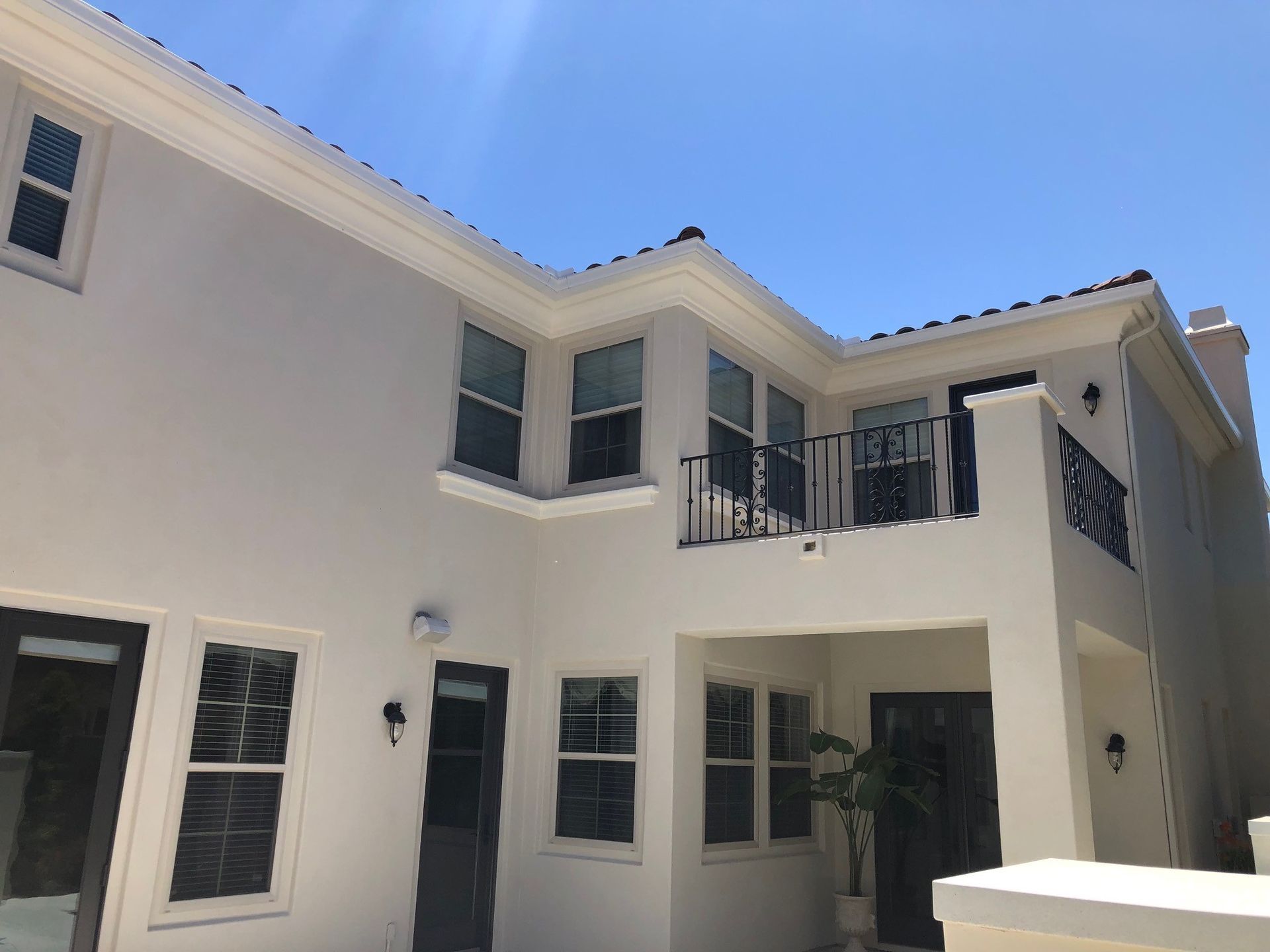 A white house with a balcony and a blue sky in the background