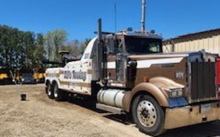 Brown and white tow truck with Route 40 Towing on the side, parked on dirt.