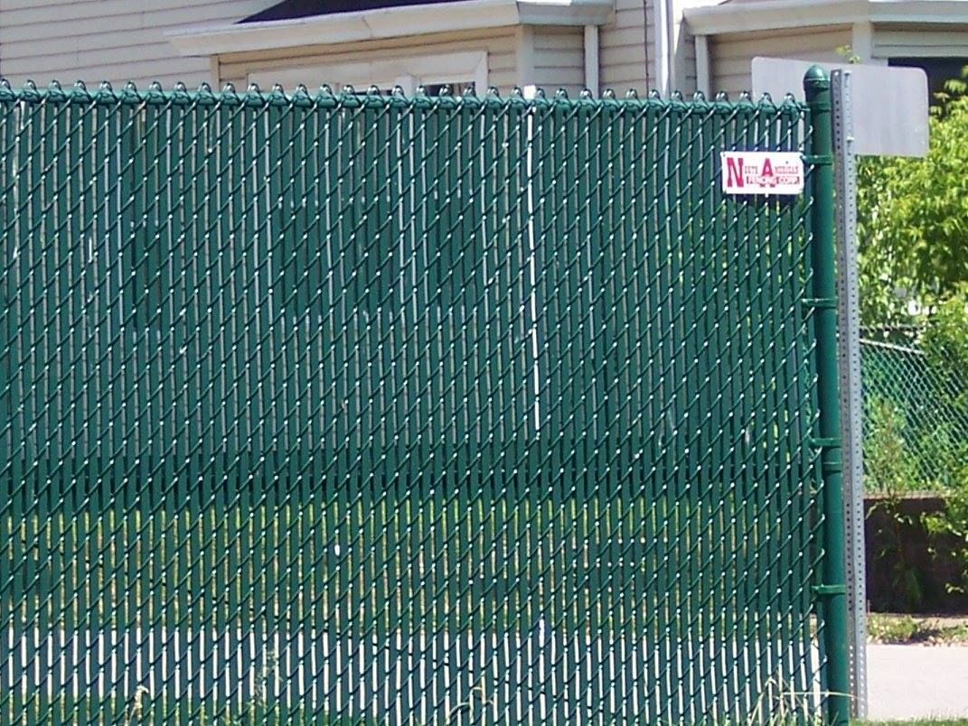 A green chain link fence with a sign that says no parking
