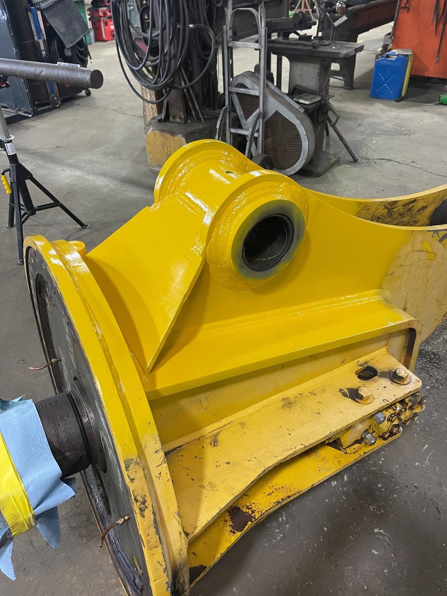Yellow industrial machine part with a large circular opening in a workshop, viewed close up.
