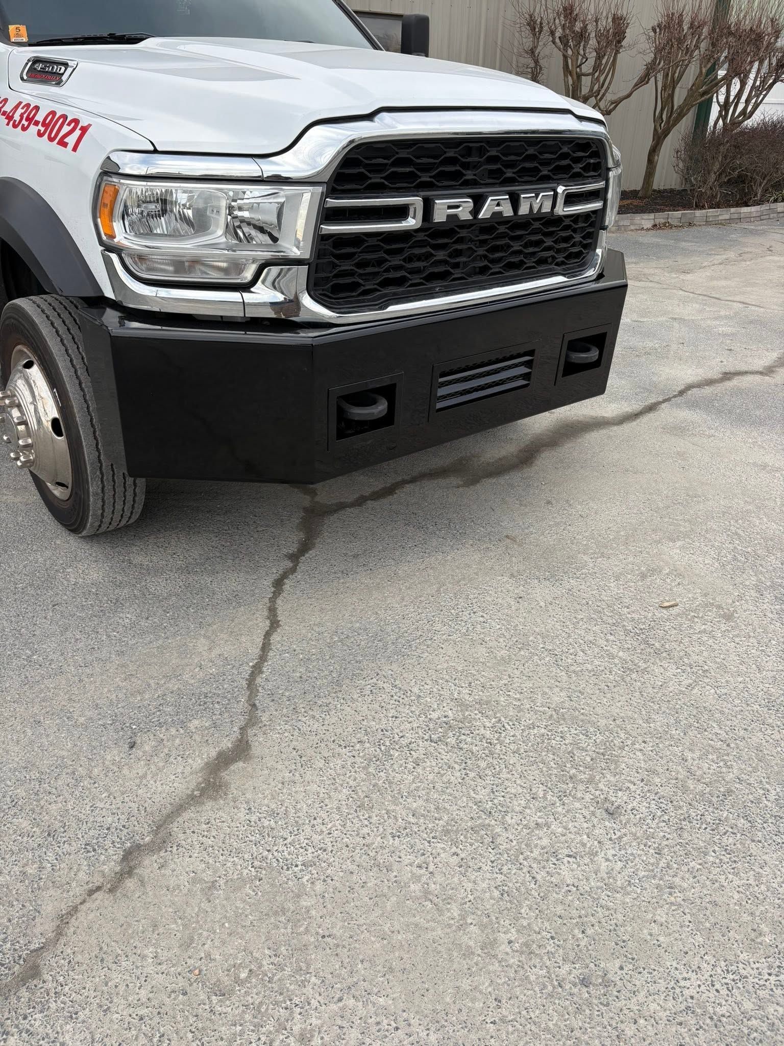 White RAM pickup truck front end parked on cracked pavement with a black grille and bumper.