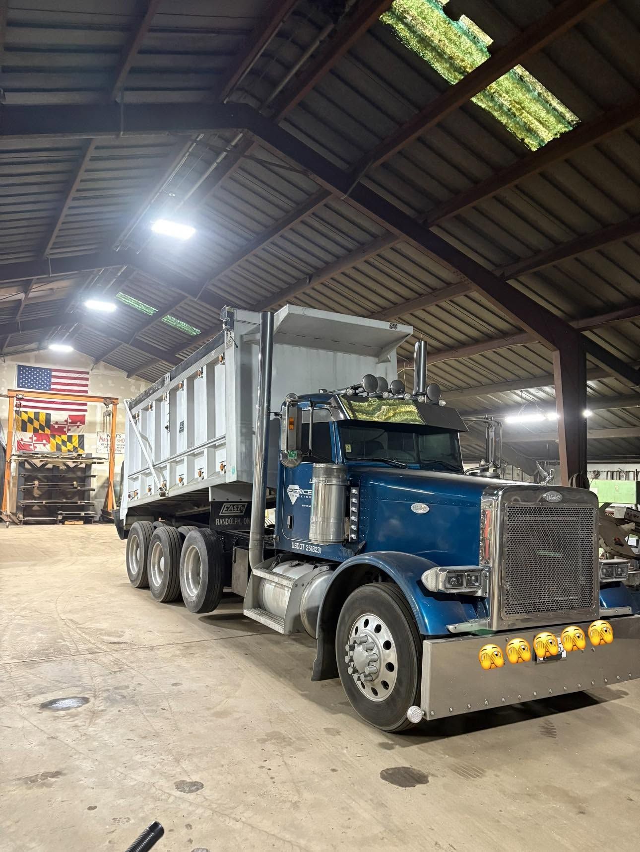 Blue semi-truck parked inside a warehouse under bright overhead lights.