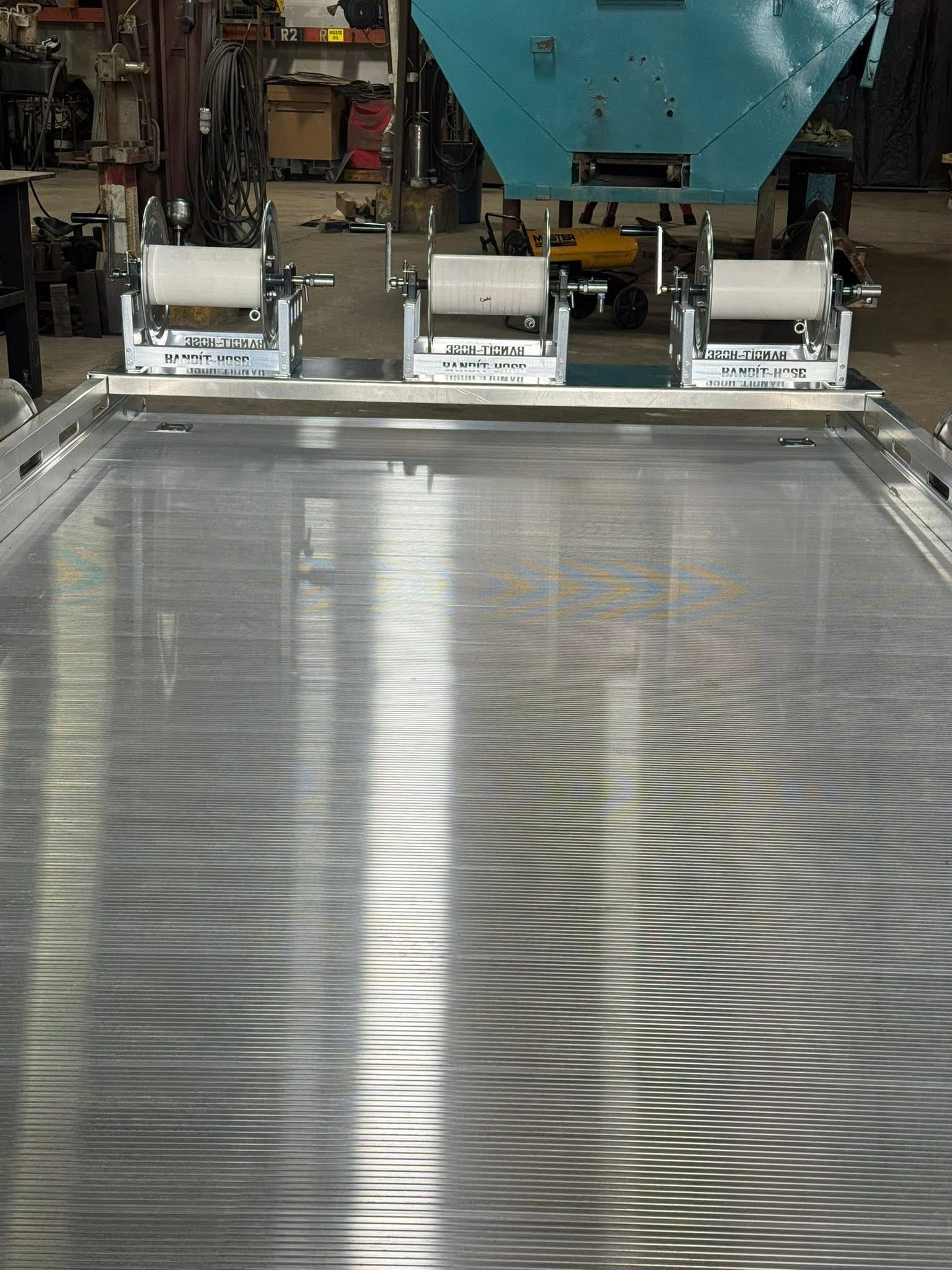 Industrial machine printing ripples on a large metal sheet in a factory.