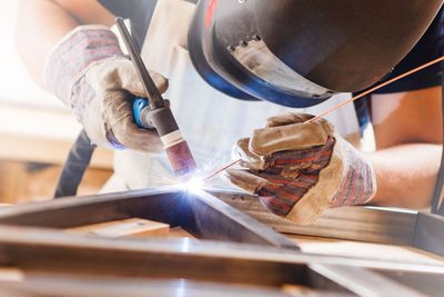 Welder joining metal beams with bright sparks in an industrial workshop
