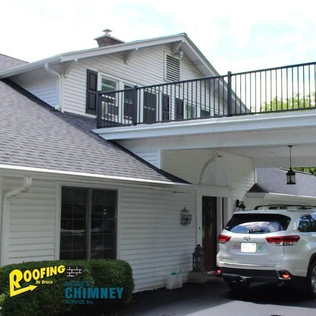 White house with gray roof, upper deck, and SUV parked under a carport