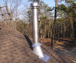 Roof vent pipe with silver chimney flashing on a shingled roof, trees in the background