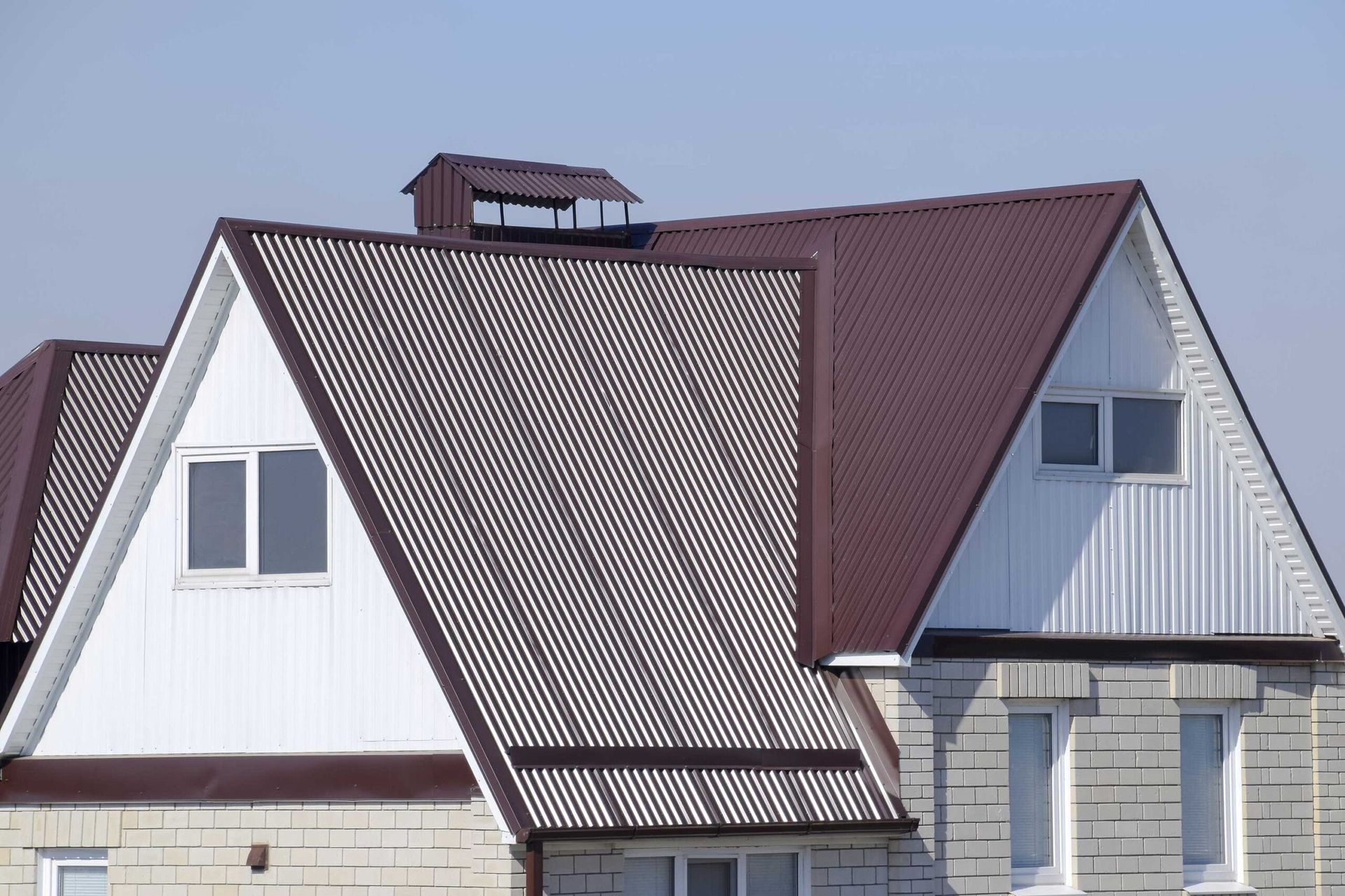 Roofs of two houses, one white and one red, under a clear sky