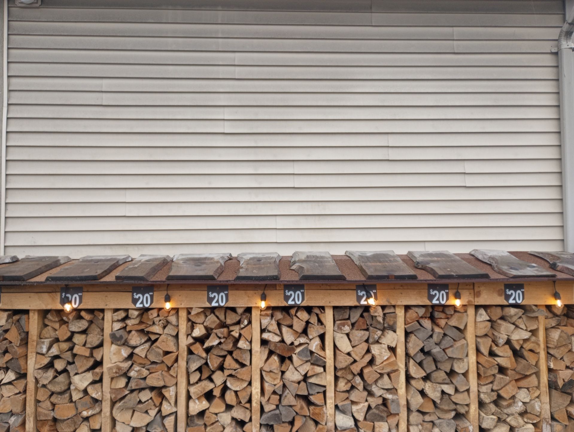 Stacked firewood beneath a white roll-up garage door, with numbered labels along the top.