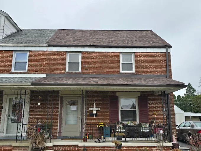 Two-story brick rowhouse with a front porch, white trim, and small decorated entryway