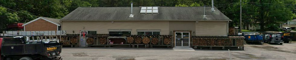 Small roadside shop with flowers outside, under a gray roof and cloudy sky, with parked cars nearby