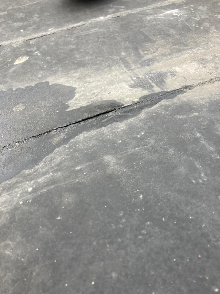 Close-up of a cracked asphalt pavement with a long dark fissure across the surface