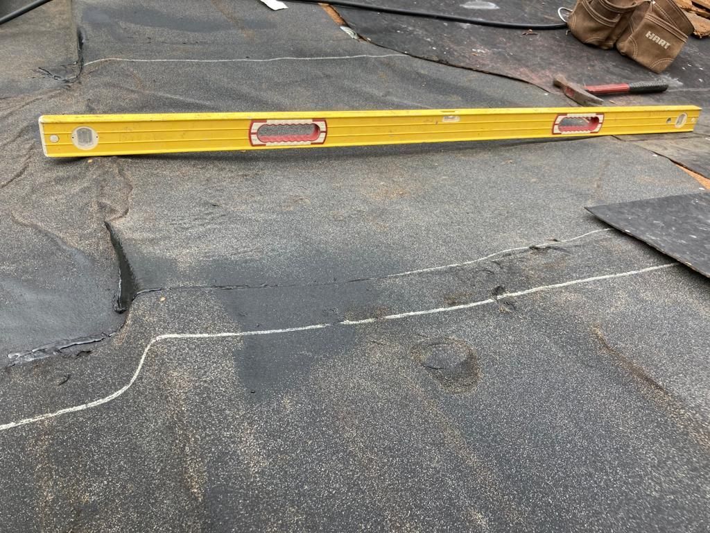 Yellow level on a dark roof with a visible seam or crack repair.
