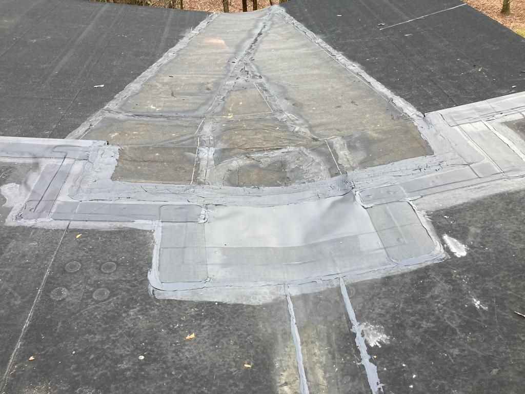 Damaged sidewalk ramp with patched concrete and cracked pavement at a street corner