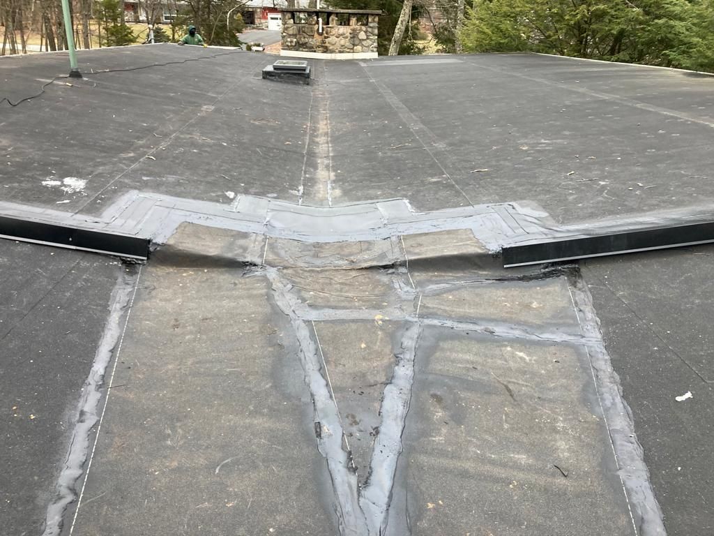 Roof with a large taped-over crack and repaired seam near the edge, viewed from above