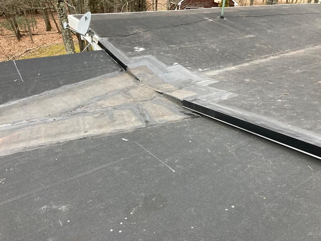 Rooftop seam repair with dark roofing membrane and a lighter patched section near the edge