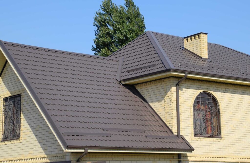 House with dark gray shingled roof and yellow brick exterior under a blue sky