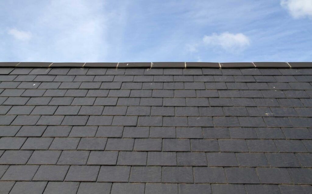 Gray shingled roof under a blue sky with a small strip of rooftop trim at the top