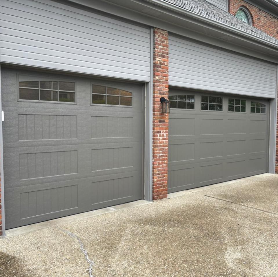 A garage door with a brick wall and a concrete driveway.